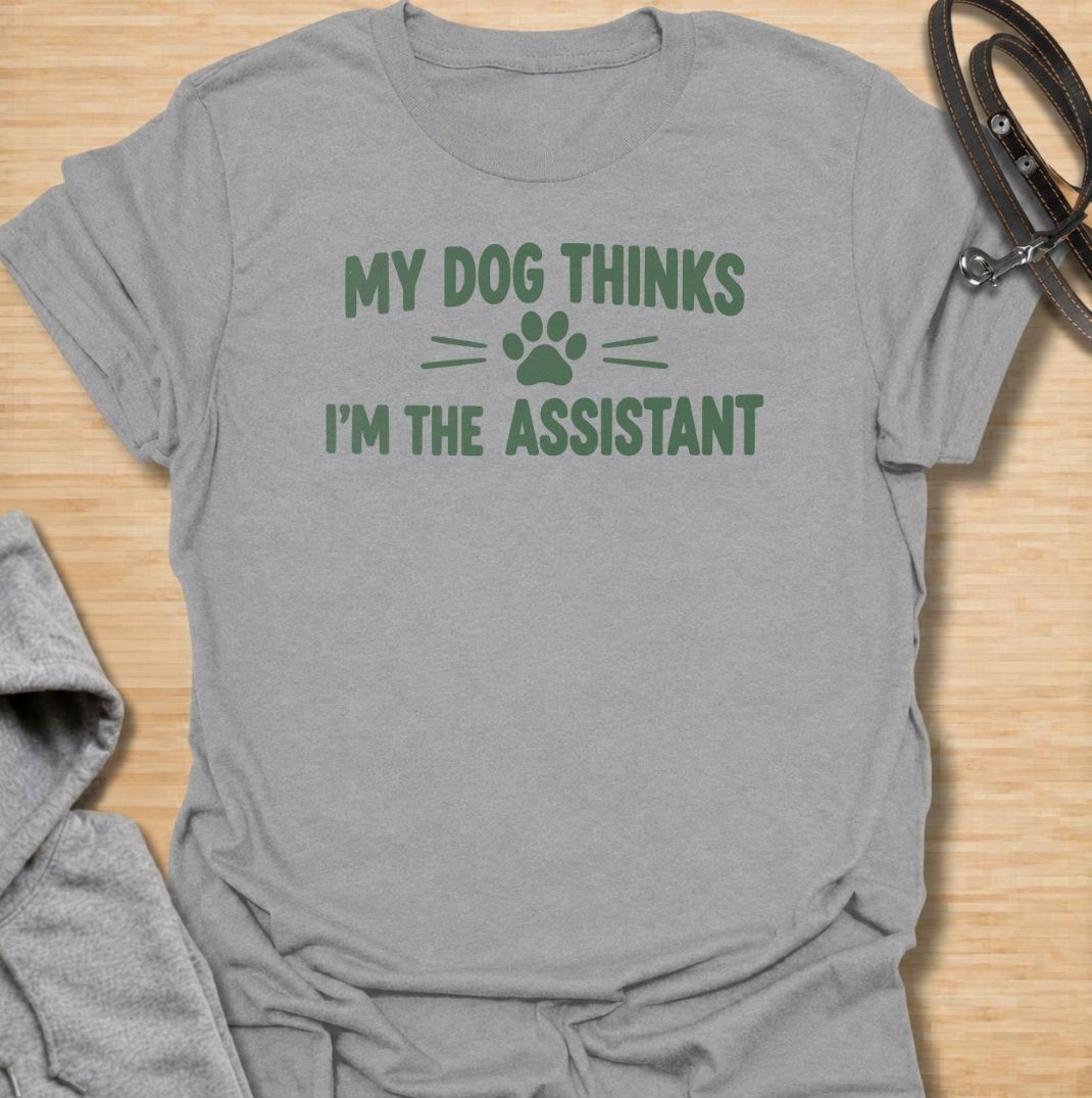 A funny dog T-shirt for anyone who knows their dog is really the one running the household. Featuring the phrase “My Dog Thinks I’m the Assistant” with a simple paw print graphic, this clean text-based design captures everyday dog-owner life with relatable humor. Perfect for dog moms, dog dads, rescue dog owners, and anyone whose pet expects first-class service at all times. A playful everyday tee for fans of funny dog sayings, pet parent humor, and general dog lover gifts.