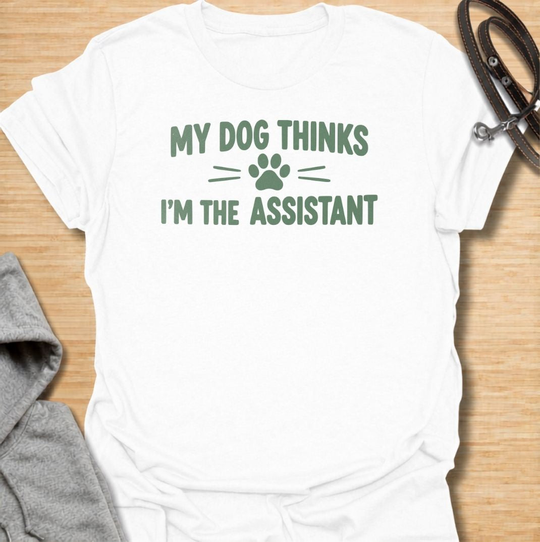 A funny dog T-shirt for anyone who knows their dog is really the one running the household. Featuring the phrase “My Dog Thinks I’m the Assistant” with a simple paw print graphic, this clean text-based design captures everyday dog-owner life with relatable humor. Perfect for dog moms, dog dads, rescue dog owners, and anyone whose pet expects first-class service at all times. A playful everyday tee for fans of funny dog sayings, pet parent humor, and general dog lover gifts.