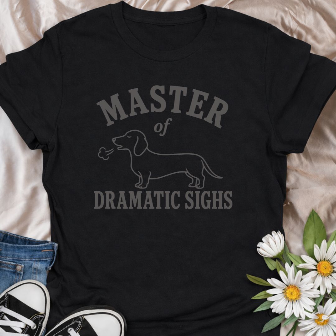 For the dachshund who turns every minor inconvenience into a full performance. This funny dachshund T-shirt features a simple sausage dog illustration with the phrase “Master of Dramatic Sighs.” A playful, easy-to-wear gift for dachshund owners, dog moms, dog dads, and anyone familiar with classic doxie drama.