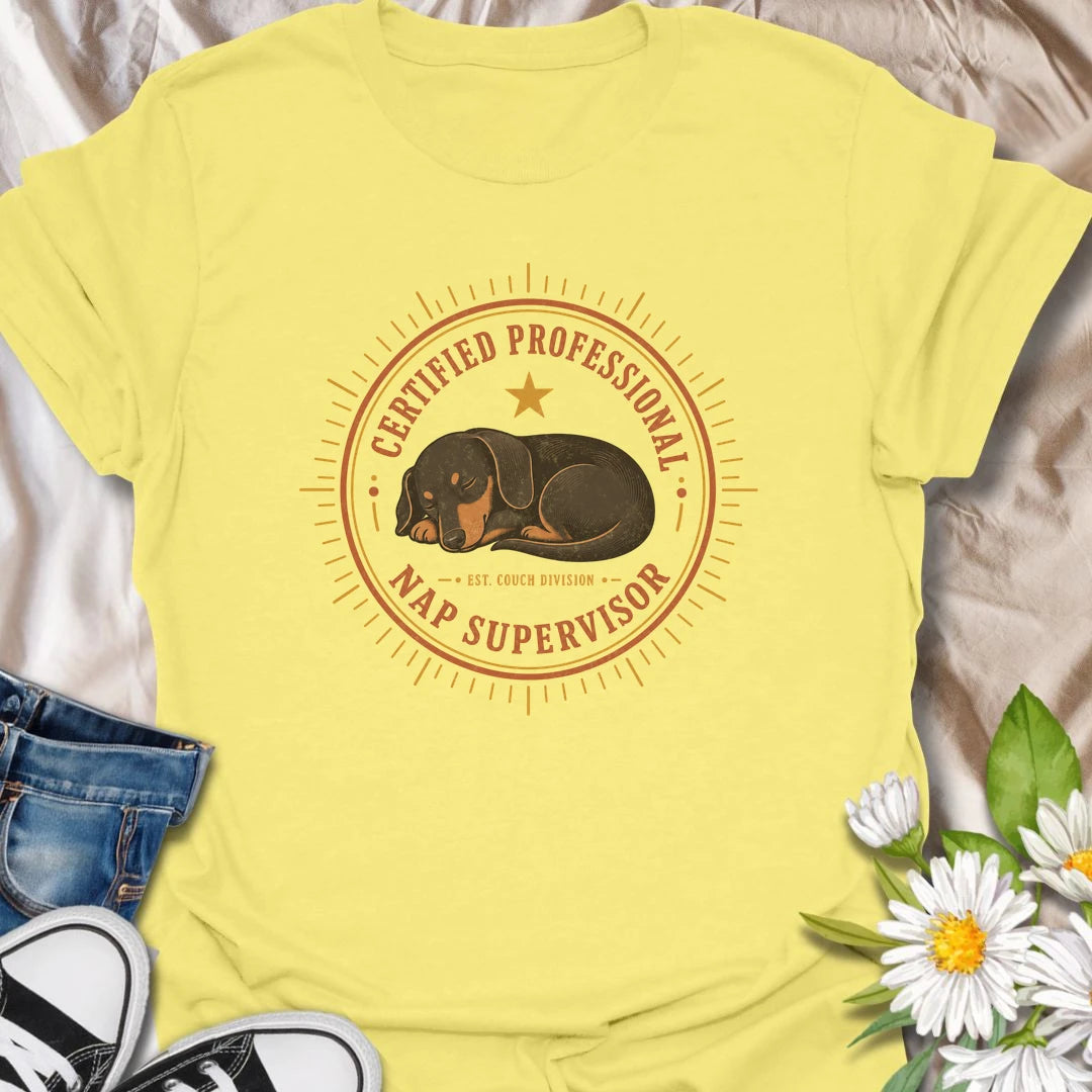 Every couch needs a certified professional nap supervisor, and dachshunds are uniquely qualified. This vintage badge-style T-shirt celebrates the sausage dog’s impressive dedication to sleeping and household supervision. A cozy, funny gift for dachshund owners and devoted doxie fans.