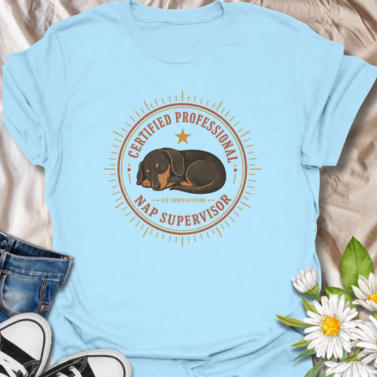 Every couch needs a certified professional nap supervisor, and dachshunds are uniquely qualified. This vintage badge-style T-shirt celebrates the sausage dog’s impressive dedication to sleeping and household supervision. A cozy, funny gift for dachshund owners and devoted doxie fans.