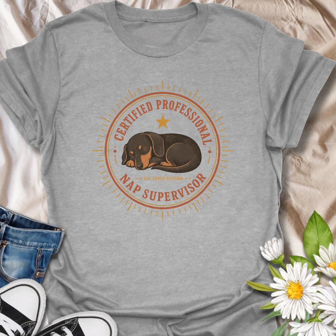 Every couch needs a certified professional nap supervisor, and dachshunds are uniquely qualified. This vintage badge-style T-shirt celebrates the sausage dog’s impressive dedication to sleeping and household supervision. A cozy, funny gift for dachshund owners and devoted doxie fans.
