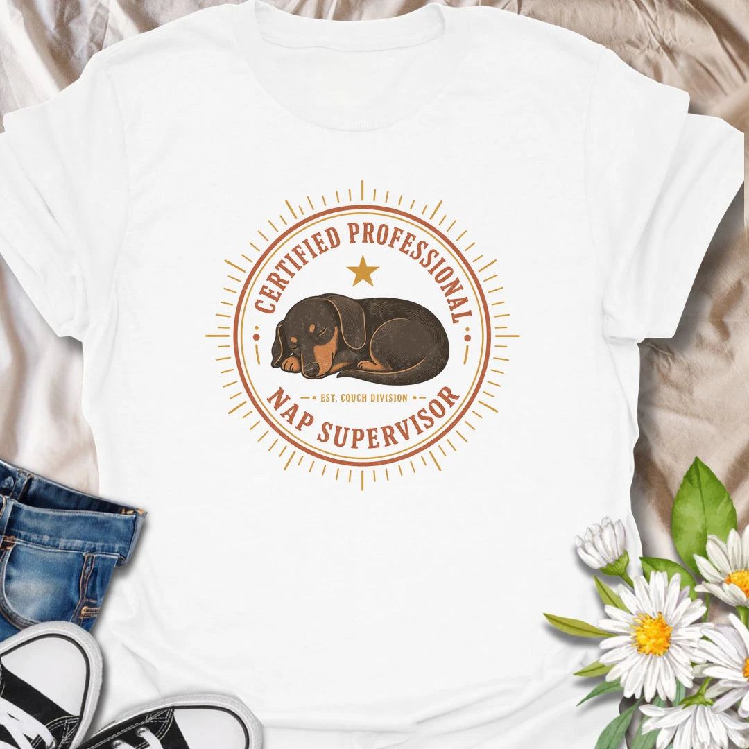Every couch needs a certified professional nap supervisor, and dachshunds are uniquely qualified. This vintage badge-style T-shirt celebrates the sausage dog’s impressive dedication to sleeping and household supervision. A cozy, funny gift for dachshund owners and devoted doxie fans.