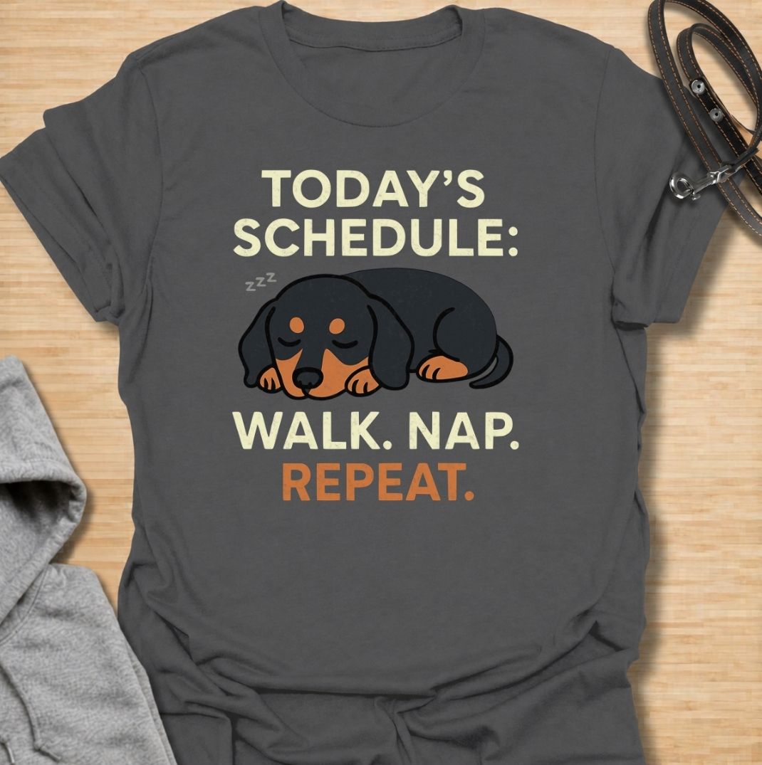 A funny dachshund T-shirt for anyone familiar with the very demanding daily routine of a sausage dog. Featuring the phrase “Today’s Schedule: Walk. Nap. Repeat.” with a sleepy dachshund illustration, this design captures the breed’s love of short adventures followed by serious rest. Perfect for dachshund moms, dachshund dads, wiener dog owners, and anyone whose dog has mastered the art of doing just enough. A playful everyday tee for fans of dachshund humor, lazy dog jokes, and breed-specific gifts.