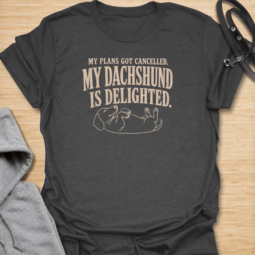 This My Plans Got Canceled My Dachshund Is Delighted t-shirt is made for doxie lovers who know their little long dog is happiest when everyone stays home. Featuring bold vintage-style typography and a relaxed dachshund lying on its back, this design has a funny, relatable dog-parent feel that wiener dog fans will instantly understand. Perfect for dachshund moms, dachshund dads, rescue dog lovers, introverts, and anyone whose dachshund fully supports canceled plans.