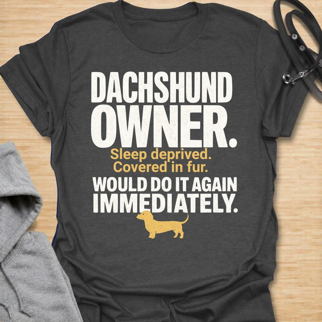 This Dachshund Owner t-shirt is made for doxie lovers who know the tiny legs come with big opinions, endless fur, and questionable sleep. Featuring bold distressed typography, a small dachshund silhouette, and the funny phrase Sleep Deprived. Covered In Fur. Would Do It Again Immediately., this design has a relatable dog-parent feel that dachshund owners will instantly understand. Perfect for dachshund moms, dachshund dads, wiener dog fans, rescue dog lovers, and anyone who knows life with a dachshund is ch