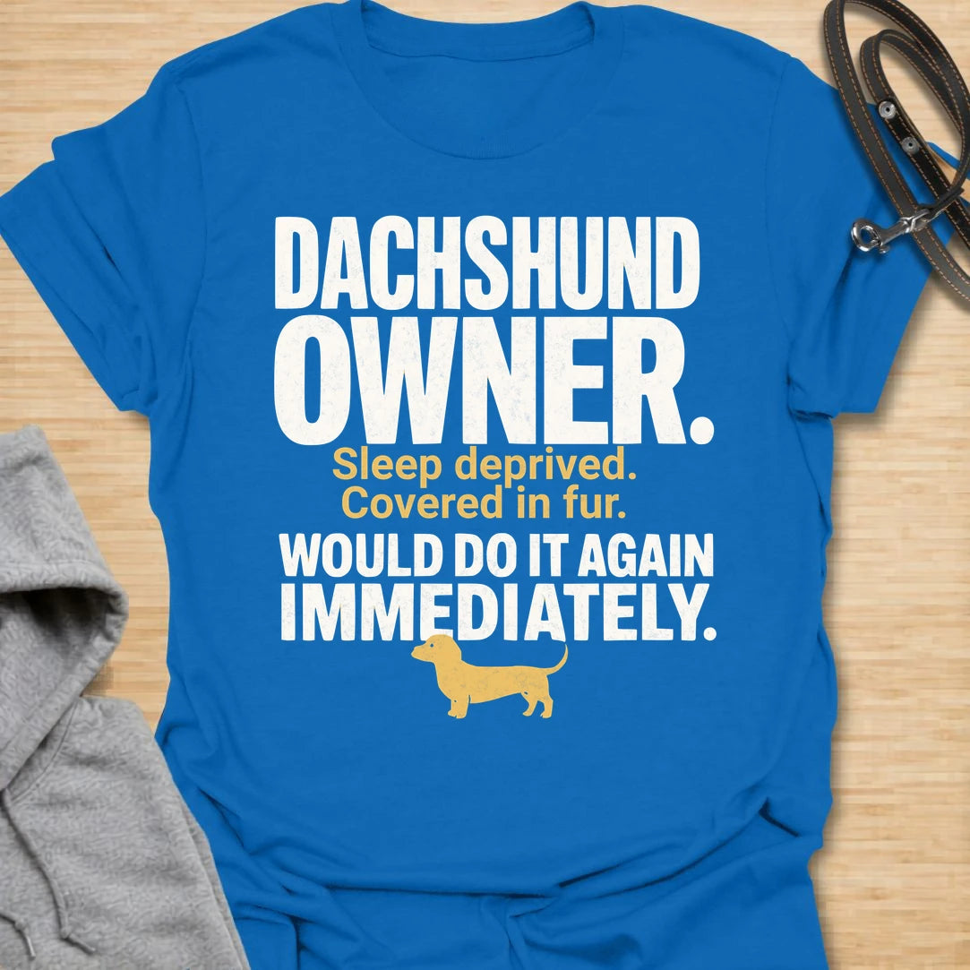 This Dachshund Owner t-shirt is made for doxie lovers who know the tiny legs come with big opinions, endless fur, and questionable sleep. Featuring bold distressed typography, a small dachshund silhouette, and the funny phrase Sleep Deprived. Covered In Fur. Would Do It Again Immediately., this design has a relatable dog-parent feel that dachshund owners will instantly understand. Perfect for dachshund moms, dachshund dads, wiener dog fans, rescue dog lovers, and anyone who knows life with a dachshund is ch