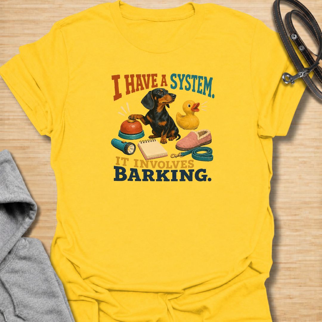 Every dachshund has a system—and it usually involves barking. This funny dachshund T-shirt features a determined sausage dog surrounded by its essential barking equipment, making it perfect for doxie owners who know the routine. A playful everyday tee and a fun gift for dachshund moms, dads, and devoted dog lovers.