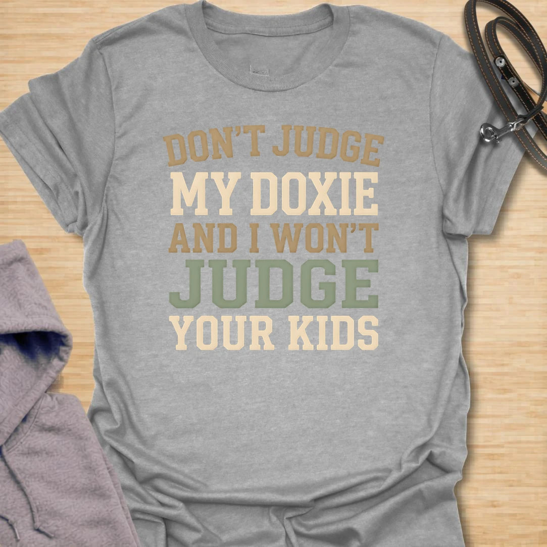 This Don’t Judge My Doxie t-shirt is made for dachshund lovers who know their little long dog may have opinions, attitude, and questionable manners, but judgment is a two-way street. Featuring bold text-only typography with the funny phrase Don’t Judge My Doxie And I Won’t Judge Your Kids, this design has a sarcastic dog-parent feel that doxie owners will instantly understand. Perfect for dachshund moms, dachshund dads, wiener dog fans, rescue dog lovers, and anyone who will always defend their doxie first.