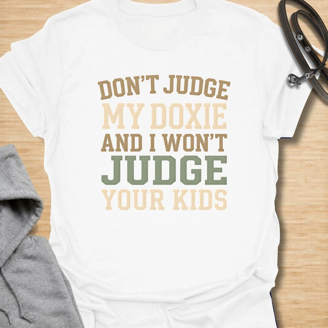 This Don’t Judge My Doxie t-shirt is made for dachshund lovers who know their little long dog may have opinions, attitude, and questionable manners, but judgment is a two-way street. Featuring bold text-only typography with the funny phrase Don’t Judge My Doxie And I Won’t Judge Your Kids, this design has a sarcastic dog-parent feel that doxie owners will instantly understand. Perfect for dachshund moms, dachshund dads, wiener dog fans, rescue dog lovers, and anyone who will always defend their doxie first.