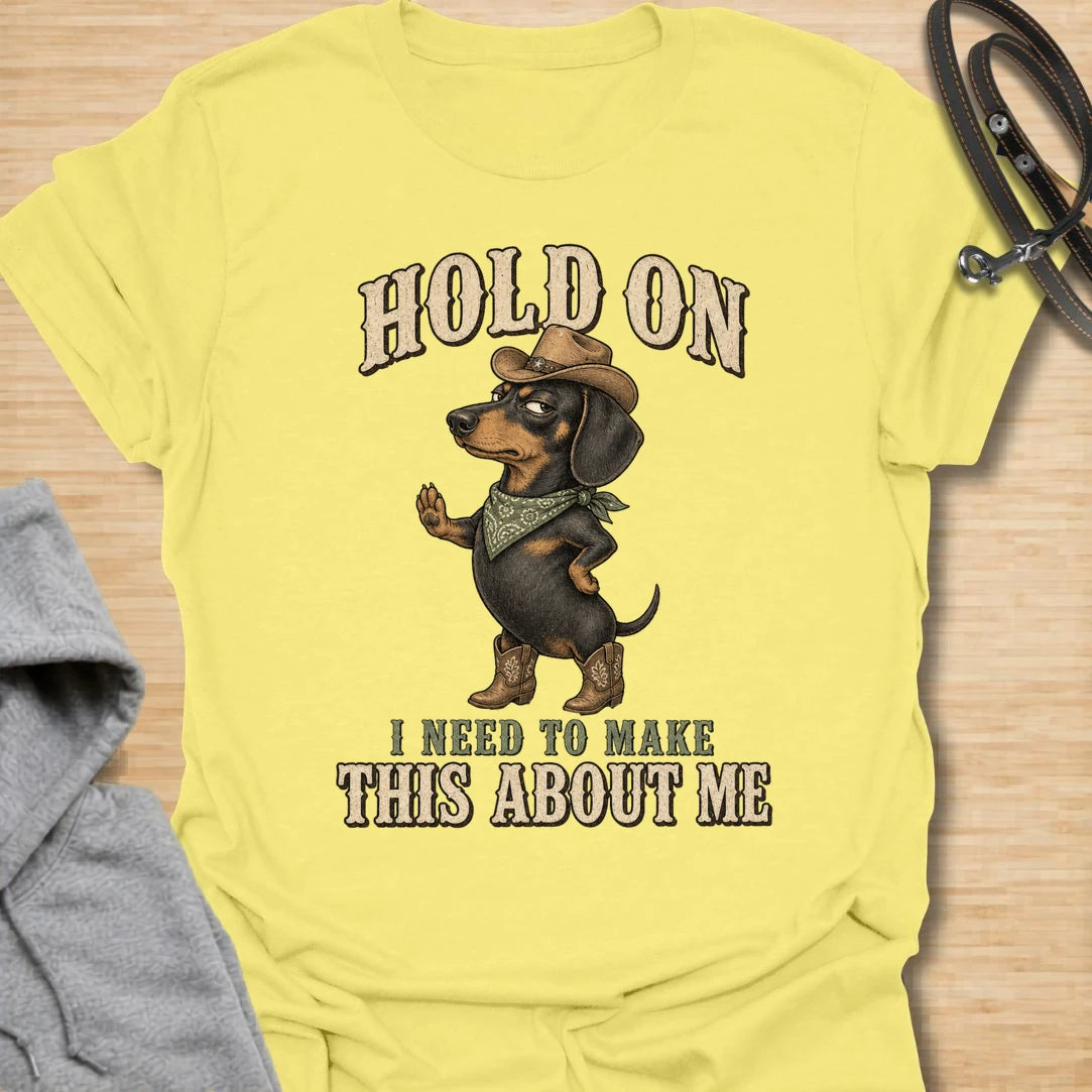 This Hold On I Need To Make This About Me t-shirt is made for dachshund lovers who know their little long dog must be the center of every conversation. Featuring a western-style dachshund in a hat, boots, and bandana with bold vintage lettering, this design has a funny main-character dog-parent feel. Perfect for dachshund moms, dachshund dads, wiener dog fans, rescue dog lovers, and anyone whose doxie always steals the spotlight.