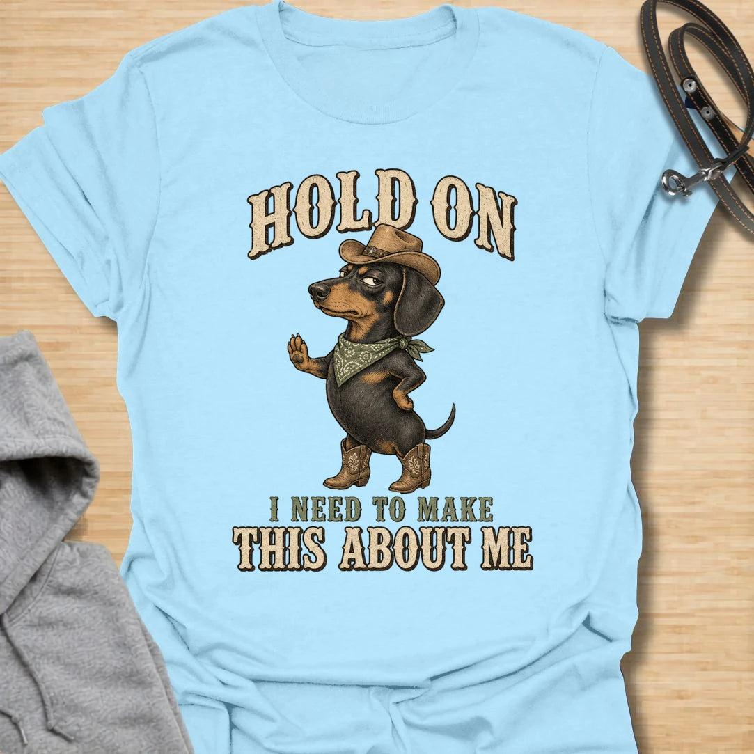 This Hold On I Need To Make This About Me t-shirt is made for dachshund lovers who know their little long dog must be the center of every conversation. Featuring a western-style dachshund in a hat, boots, and bandana with bold vintage lettering, this design has a funny main-character dog-parent feel. Perfect for dachshund moms, dachshund dads, wiener dog fans, rescue dog lovers, and anyone whose doxie always steals the spotlight.