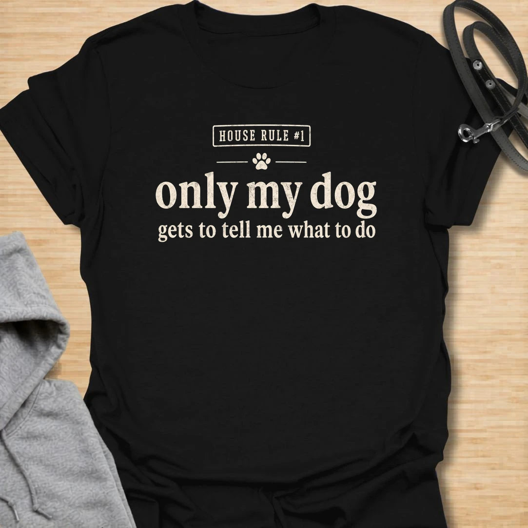 This Only My Dog Gets To Tell Me What To Do t-shirt is made for dog owners who know exactly who is really in charge at home. Featuring a simple text-only layout with a small paw print and the phrase House Rule #1, this design has a funny, relatable dog-parent feel that is easy to wear every day. Perfect for dog moms, dog dads, rescue dog owners, pet parents, and anyone who happily takes orders from their four-legged boss.Black