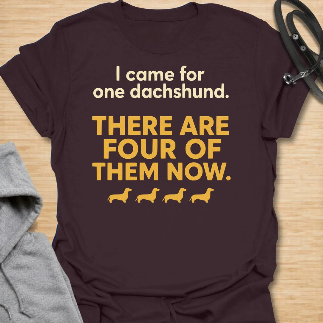 This I Came For One Dachshund t-shirt is made for doxie lovers who know one tiny long dog somehow turns into a whole little pack. Featuring bold text-only typography, four small dachshund silhouettes, and the funny phrase There Are Four Of Them Now, this design has a simple, relatable dog-parent feel that wiener dog fans will instantly understand. Perfect for dachshund moms, dachshund dads, multi-dachshund homes, rescue dog lovers, and anyone who accidentally became a full-time doxie collector.