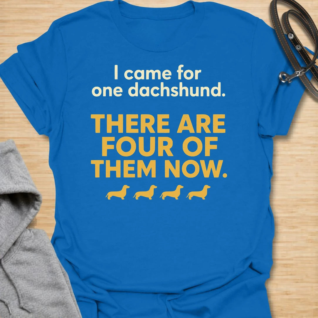 This I Came For One Dachshund t-shirt is made for doxie lovers who know one tiny long dog somehow turns into a whole little pack. Featuring bold text-only typography, four small dachshund silhouettes, and the funny phrase There Are Four Of Them Now, this design has a simple, relatable dog-parent feel that wiener dog fans will instantly understand. Perfect for dachshund moms, dachshund dads, multi-dachshund homes, rescue dog lovers, and anyone who accidentally became a full-time doxie collector.