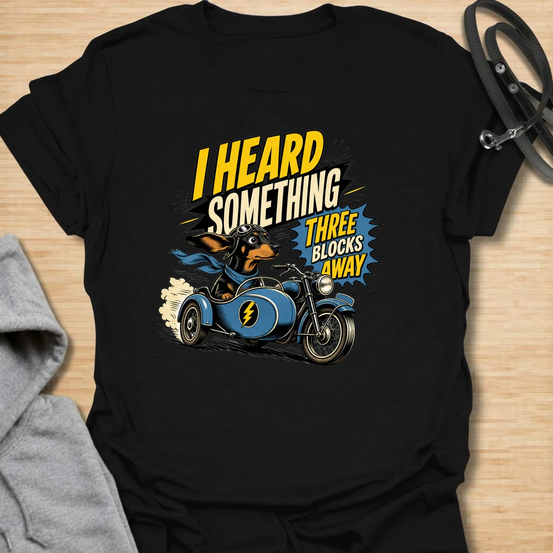 Three Blocks Away t-shirt for dachshund lovers who know their little dog hears absolutely everything. This funny design features a speedy wiener dog racing in a vintage car with bold retro lettering and chaotic doxie energy. Perfect for dachshund moms, doxie dads, sausage dog owners, and anyone living with a tiny dog who is always on neighborhood patrol.