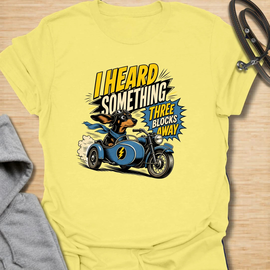 Three Blocks Away t-shirt for dachshund lovers who know their little dog hears absolutely everything. This funny design features a speedy wiener dog racing in a vintage car with bold retro lettering and chaotic doxie energy. Perfect for dachshund moms, doxie dads, sausage dog owners, and anyone living with a tiny dog who is always on neighborhood patrol.