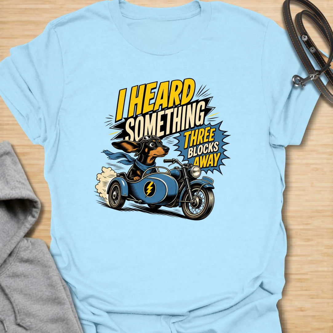 Three Blocks Away t-shirt for dachshund lovers who know their little dog hears absolutely everything. This funny design features a speedy wiener dog racing in a vintage car with bold retro lettering and chaotic doxie energy. Perfect for dachshund moms, doxie dads, sausage dog owners, and anyone living with a tiny dog who is always on neighborhood patrol.
