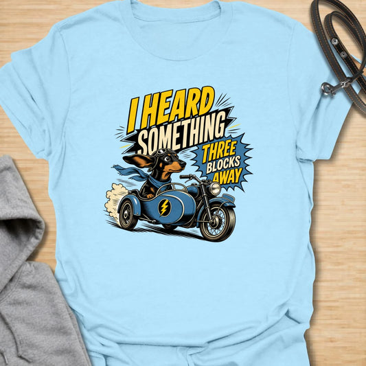 Three Blocks Away t-shirt for dachshund lovers who know their little dog hears absolutely everything. This funny design features a speedy wiener dog racing in a vintage car with bold retro lettering and chaotic doxie energy. Perfect for dachshund moms, doxie dads, sausage dog owners, and anyone living with a tiny dog who is always on neighborhood patrol.