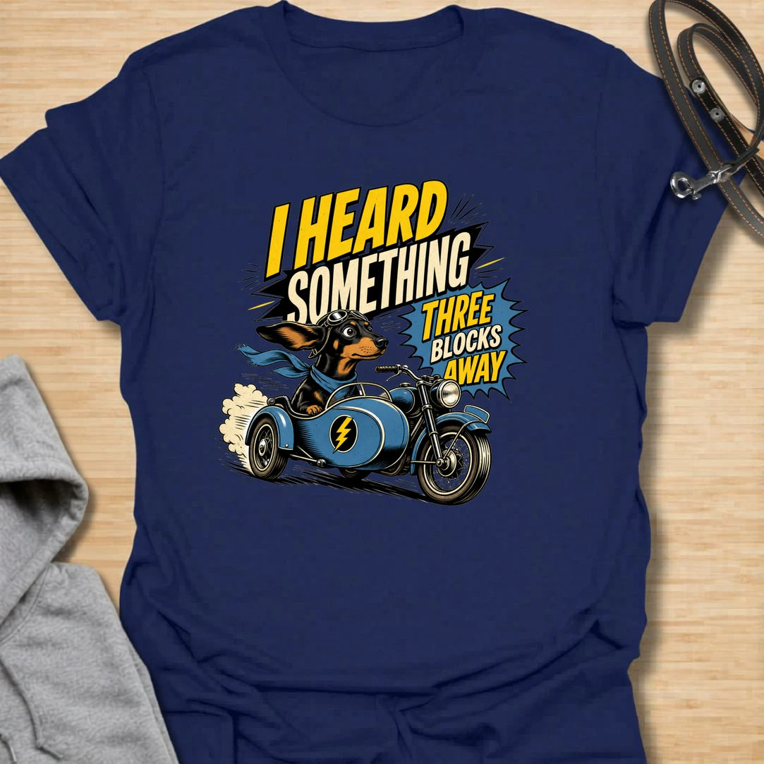 Three Blocks Away t-shirt for dachshund lovers who know their little dog hears absolutely everything. This funny design features a speedy wiener dog racing in a vintage car with bold retro lettering and chaotic doxie energy. Perfect for dachshund moms, doxie dads, sausage dog owners, and anyone living with a tiny dog who is always on neighborhood patrol.