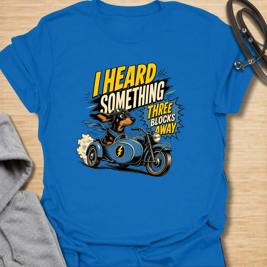 Three Blocks Away t-shirt for dachshund lovers who know their little dog hears absolutely everything. This funny design features a speedy wiener dog racing in a vintage car with bold retro lettering and chaotic doxie energy. Perfect for dachshund moms, doxie dads, sausage dog owners, and anyone living with a tiny dog who is always on neighborhood patrol.
