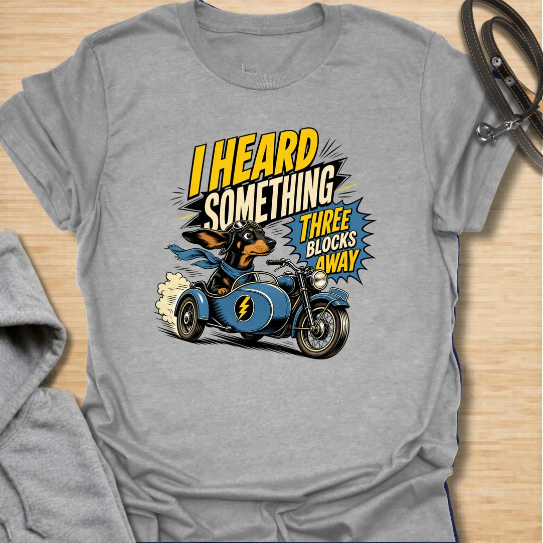 Three Blocks Away t-shirt for dachshund lovers who know their little dog hears absolutely everything. This funny design features a speedy wiener dog racing in a vintage car with bold retro lettering and chaotic doxie energy. Perfect for dachshund moms, doxie dads, sausage dog owners, and anyone living with a tiny dog who is always on neighborhood patrol.