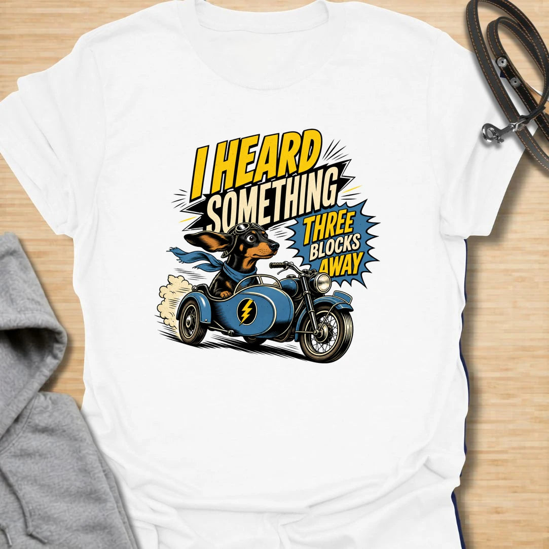 Three Blocks Away t-shirt for dachshund lovers who know their little dog hears absolutely everything. This funny design features a speedy wiener dog racing in a vintage car with bold retro lettering and chaotic doxie energy. Perfect for dachshund moms, doxie dads, sausage dog owners, and anyone living with a tiny dog who is always on neighborhood patrol.