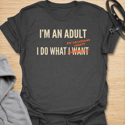 This funny dachshund t-shirt is made for anyone who technically makes their own decisions, but still answers to their doxie. The bold text layout and crossed-out wording give the design a modern, relatable dog parent feel. It is perfect for dachshund moms, doxie dads, and anyone whose little long dog quietly runs the house. A great casual shirt for dog lovers who know adulting mostly means doing what the dachshund wants.
