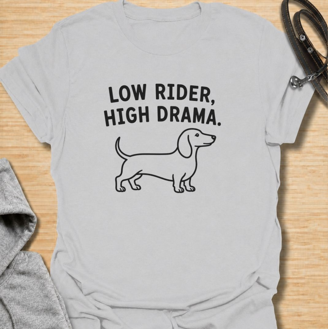 Low to the ground and never short on drama. This funny dachshund T-shirt features a clean minimalist sausage dog illustration with the phrase “Low Rider, High Drama.” A simple, wearable gift for dachshund owners, doxie lovers, dog moms, and anyone familiar with the breed’s larger-than-life personality.