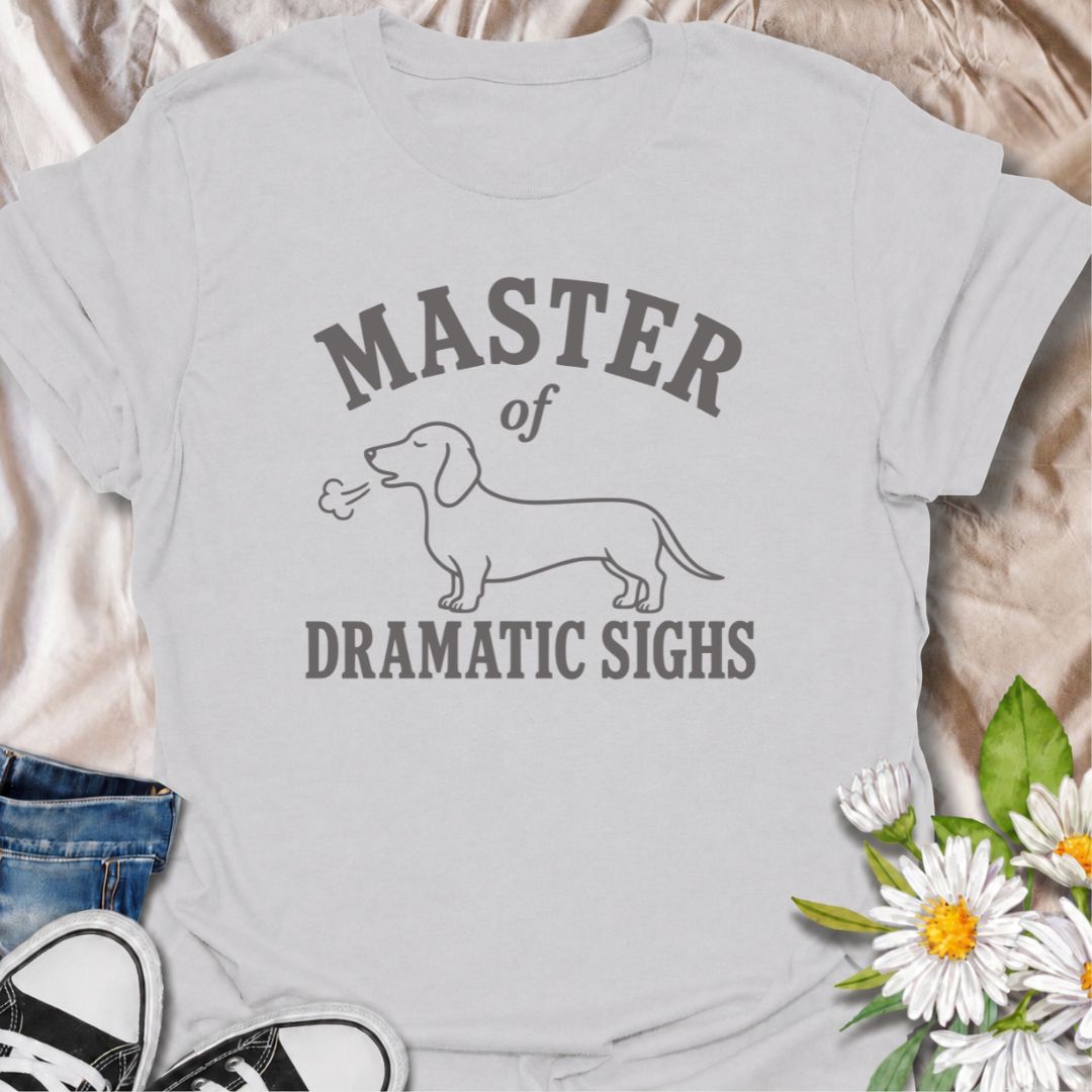 For the dachshund who turns every minor inconvenience into a full performance. This funny dachshund T-shirt features a simple sausage dog illustration with the phrase “Master of Dramatic Sighs.” A playful, easy-to-wear gift for dachshund owners, dog moms, dog dads, and anyone familiar with classic doxie drama.