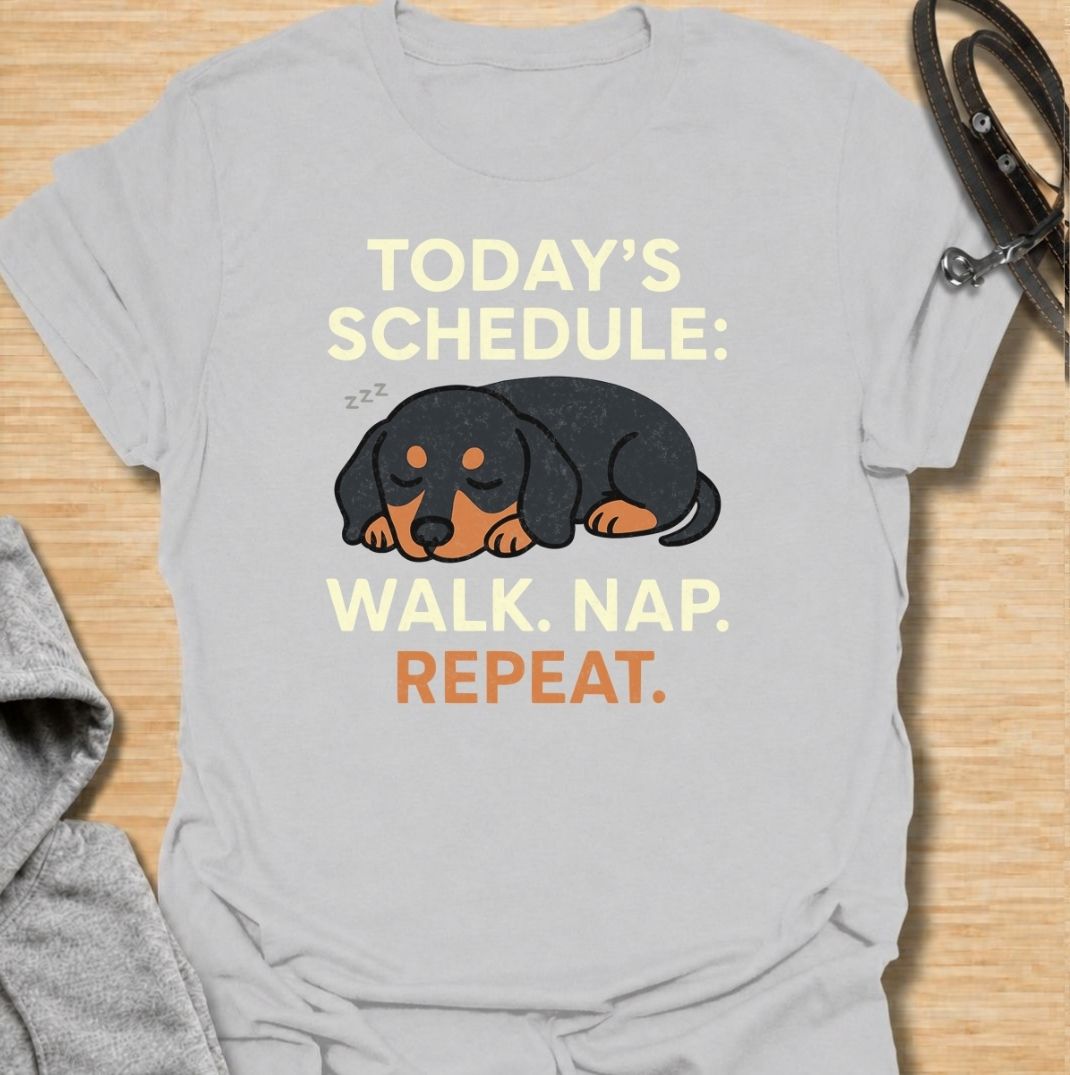 A funny dachshund T-shirt for anyone familiar with the very demanding daily routine of a sausage dog. Featuring the phrase “Today’s Schedule: Walk. Nap. Repeat.” with a sleepy dachshund illustration, this design captures the breed’s love of short adventures followed by serious rest. Perfect for dachshund moms, dachshund dads, wiener dog owners, and anyone whose dog has mastered the art of doing just enough. A playful everyday tee for fans of dachshund humor, lazy dog jokes, and breed-specific gifts.
