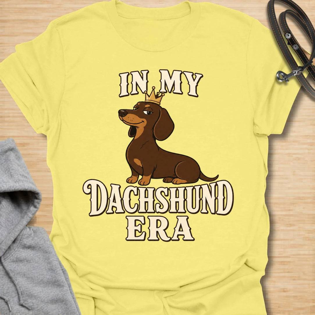 This In My Dachshund Era t-shirt is made for doxie lovers who know their little long dog is not just a pet, it is a whole lifestyle. Featuring a cute dachshund wearing a crown with bold retro-style text, this fun breed-specific design is great for dachshund moms, dachshund dads, wiener dog fans, rescue dog lovers, and anyone proudly living their dachshund era.