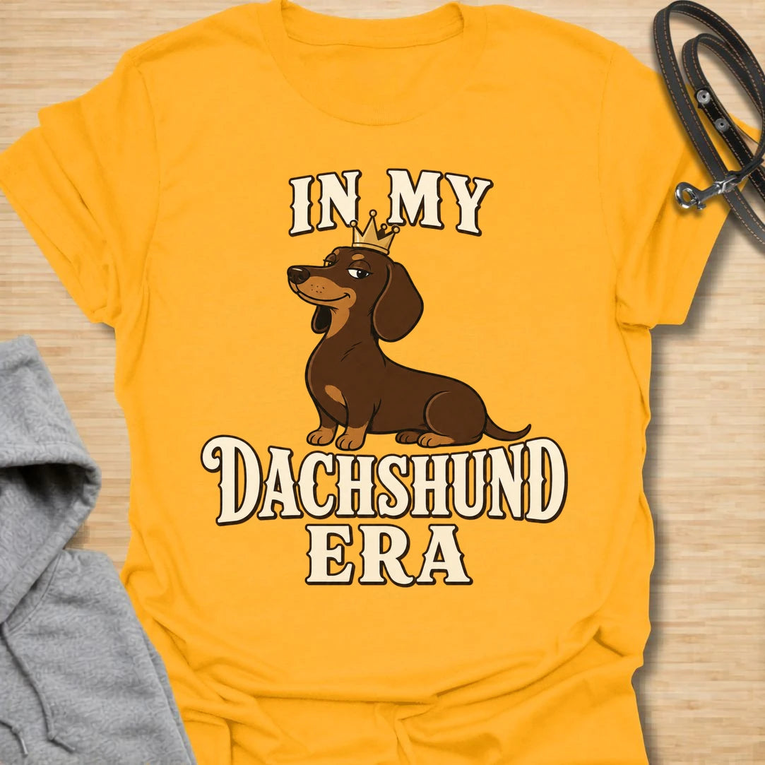 This In My Dachshund Era t-shirt is made for doxie lovers who know their little long dog is not just a pet, it is a whole lifestyle. Featuring a cute dachshund wearing a crown with bold retro-style text, this fun breed-specific design is great for dachshund moms, dachshund dads, wiener dog fans, rescue dog lovers, and anyone proudly living their dachshund era.