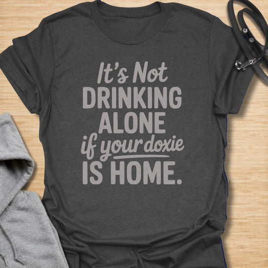 Drinking Alone Doxie t-shirt for dachshund owners who know a doxie at home means you are never really drinking alone. This funny text design says “It’s Not Drinking Alone If Your Doxie Is Home,” making it perfect for wine lovers, dog moms, and sausage dog fans. A fun gift for dachshund lovers who enjoy cozy nights in with their favorite four-legged companion.