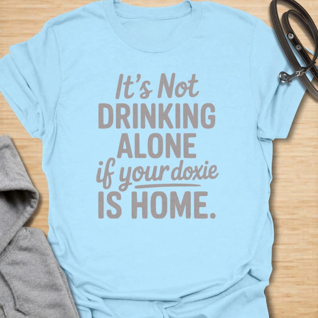 Drinking Alone Doxie t-shirt for dachshund owners who know a doxie at home means you are never really drinking alone. This funny text design says “It’s Not Drinking Alone If Your Doxie Is Home,” making it perfect for wine lovers, dog moms, and sausage dog fans. A fun gift for dachshund lovers who enjoy cozy nights in with their favorite four-legged companion.