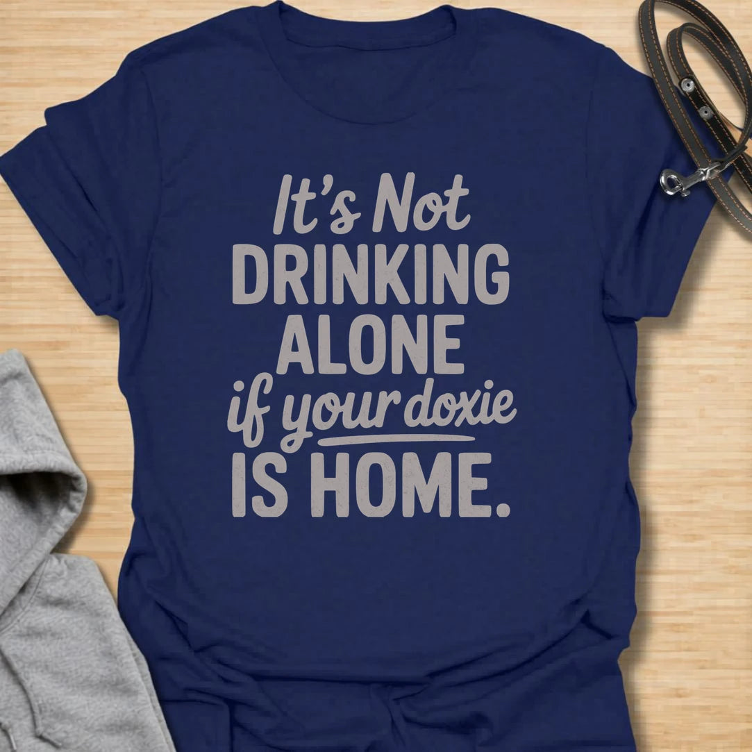 Drinking Alone Doxie t-shirt for dachshund owners who know a doxie at home means you are never really drinking alone. This funny text design says “It’s Not Drinking Alone If Your Doxie Is Home,” making it perfect for wine lovers, dog moms, and sausage dog fans. A fun gift for dachshund lovers who enjoy cozy nights in with their favorite four-legged companion.