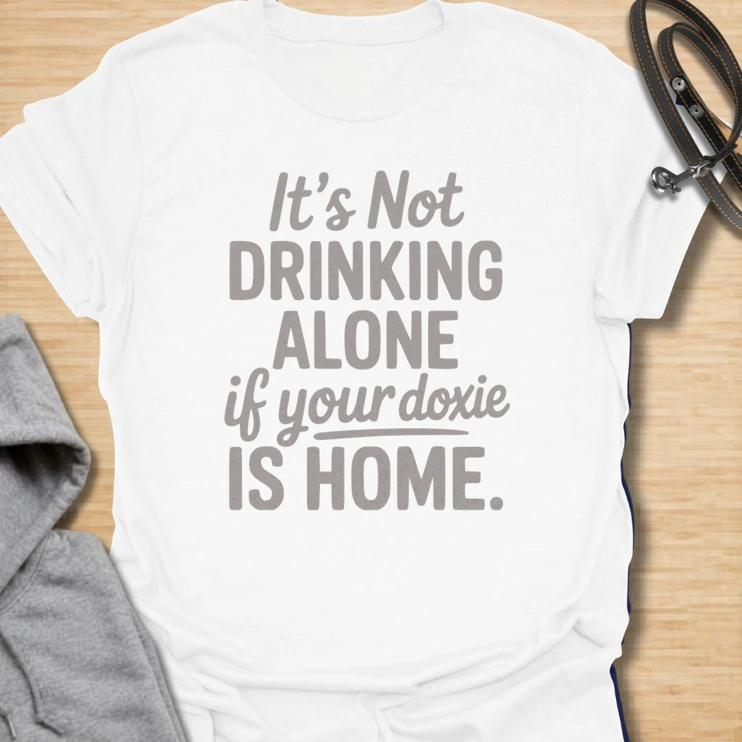 Drinking Alone Doxie t-shirt for dachshund owners who know a doxie at home means you are never really drinking alone. This funny text design says “It’s Not Drinking Alone If Your Doxie Is Home,” making it perfect for wine lovers, dog moms, and sausage dog fans. A fun gift for dachshund lovers who enjoy cozy nights in with their favorite four-legged companion.