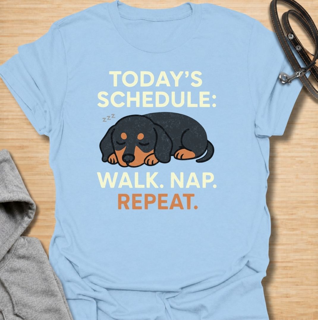 A funny dachshund T-shirt for anyone familiar with the very demanding daily routine of a sausage dog. Featuring the phrase “Today’s Schedule: Walk. Nap. Repeat.” with a sleepy dachshund illustration, this design captures the breed’s love of short adventures followed by serious rest. Perfect for dachshund moms, dachshund dads, wiener dog owners, and anyone whose dog has mastered the art of doing just enough. A playful everyday tee for fans of dachshund humor, lazy dog jokes, and breed-specific gifts.