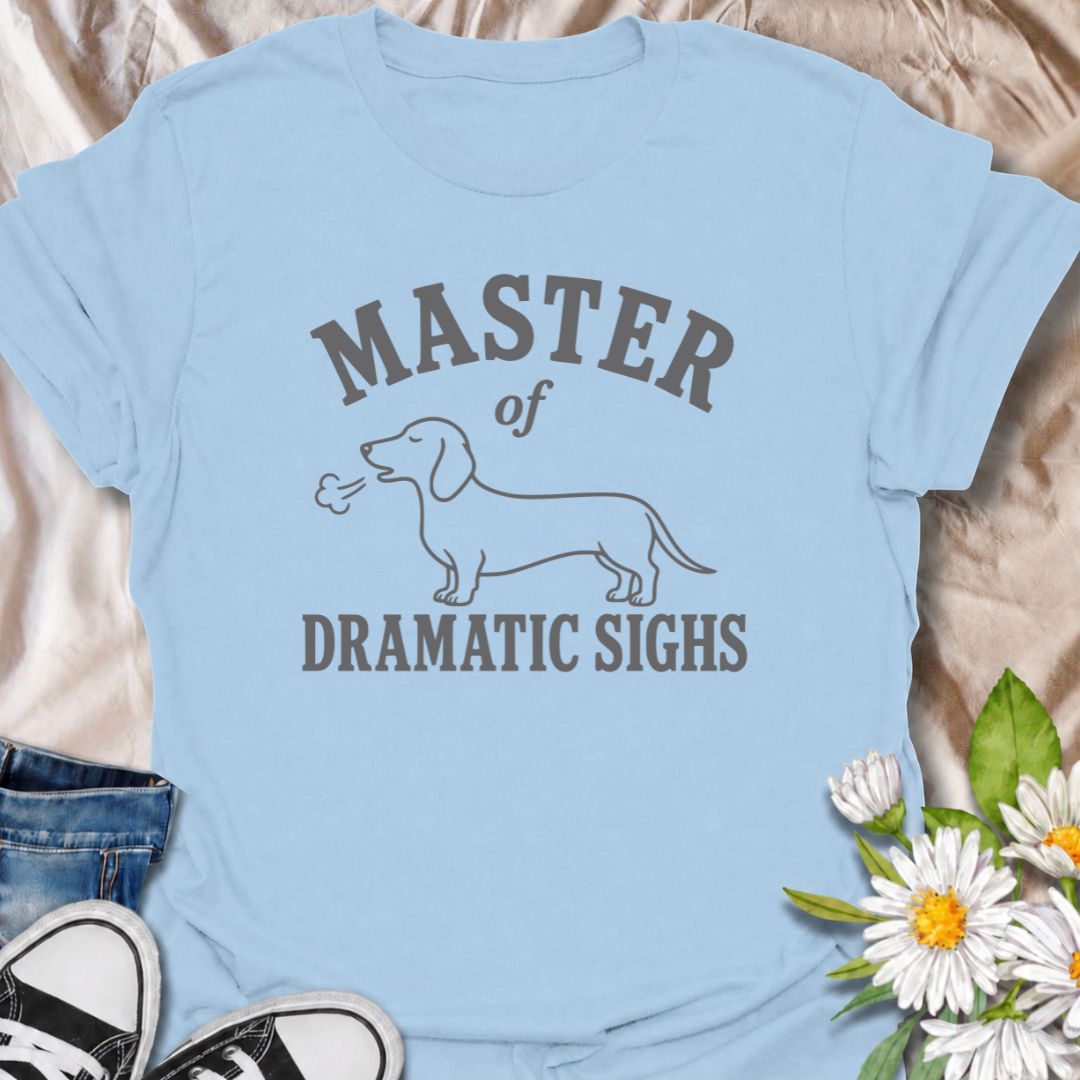 For the dachshund who turns every minor inconvenience into a full performance. This funny dachshund T-shirt features a simple sausage dog illustration with the phrase “Master of Dramatic Sighs.” A playful, easy-to-wear gift for dachshund owners, dog moms, dog dads, and anyone familiar with classic doxie drama.