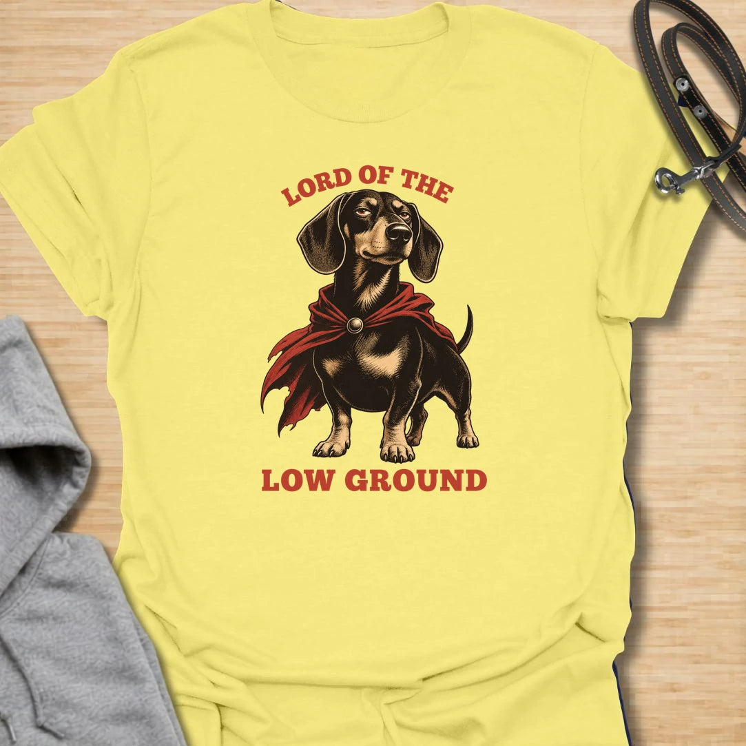 Funny dachshund t-shirt featuring a proud doxie in a dramatic cape with the phrase “Lord of the Low Ground.” This design is perfect for dachshund lovers who know these tiny-legged dogs have huge confidence, royal attitude, and absolutely no shortage of personality. A great gift for dog moms, dog dads, wiener dog owners, and anyone who loves funny sausage dog apparel. Ideal for fans of bold dachshund humor, short dog jokes, and playful breed-specific t-shirts.