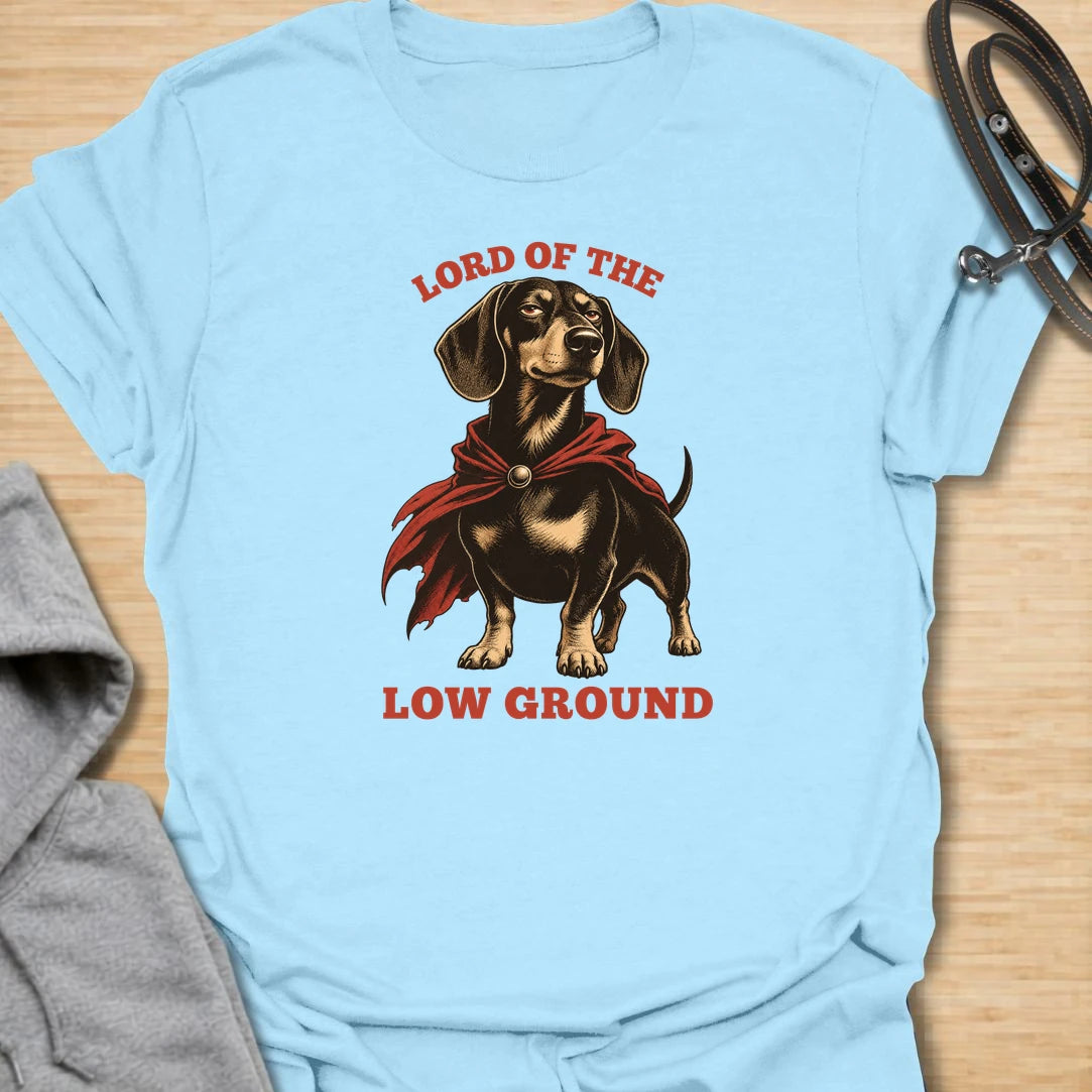 Funny dachshund t-shirt featuring a proud doxie in a dramatic cape with the phrase “Lord of the Low Ground.” This design is perfect for dachshund lovers who know these tiny-legged dogs have huge confidence, royal attitude, and absolutely no shortage of personality. A great gift for dog moms, dog dads, wiener dog owners, and anyone who loves funny sausage dog apparel. Ideal for fans of bold dachshund humor, short dog jokes, and playful breed-specific t-shirts.
