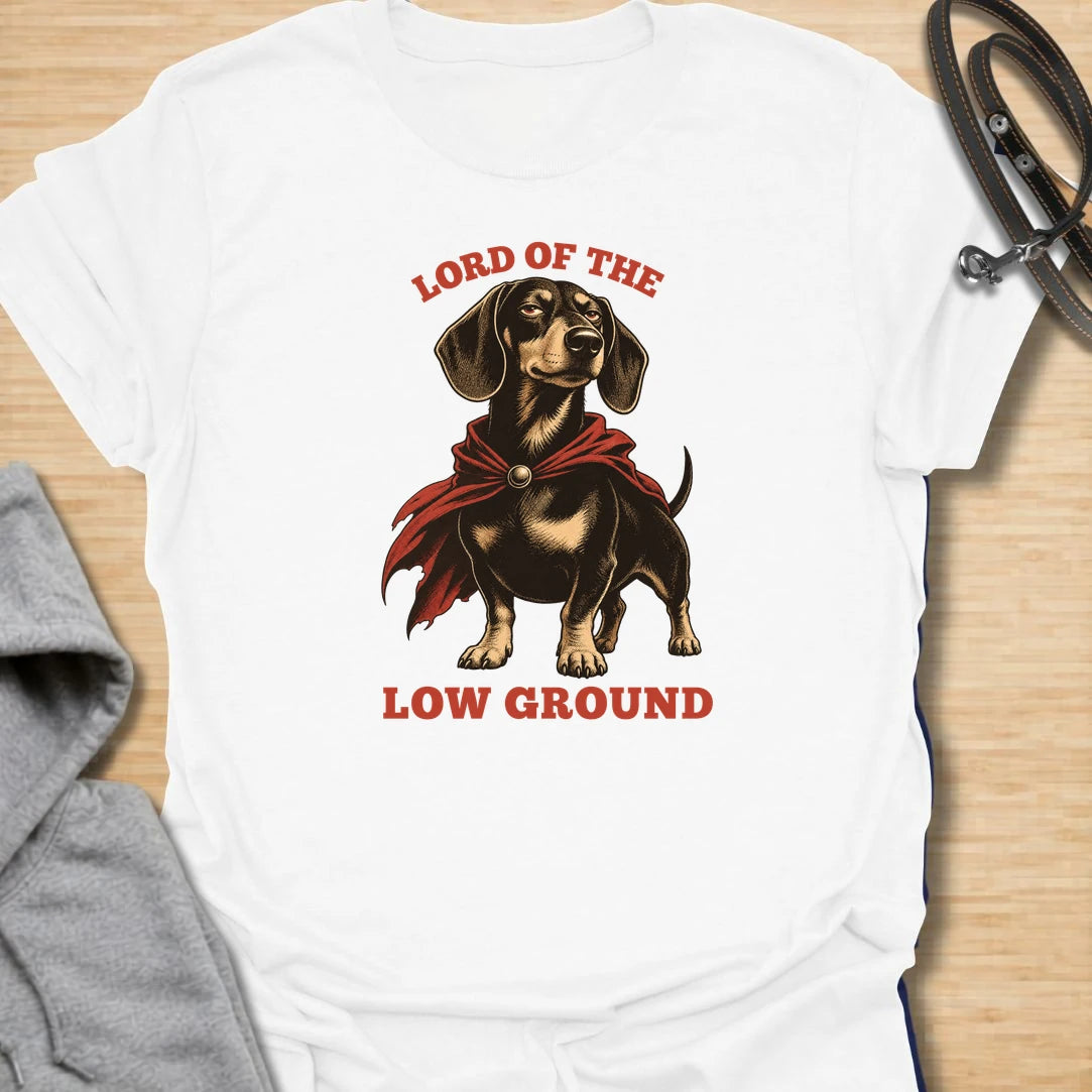 Funny dachshund t-shirt featuring a proud doxie in a dramatic cape with the phrase “Lord of the Low Ground.” This design is perfect for dachshund lovers who know these tiny-legged dogs have huge confidence, royal attitude, and absolutely no shortage of personality. A great gift for dog moms, dog dads, wiener dog owners, and anyone who loves funny sausage dog apparel. Ideal for fans of bold dachshund humor, short dog jokes, and playful breed-specific t-shirts.
