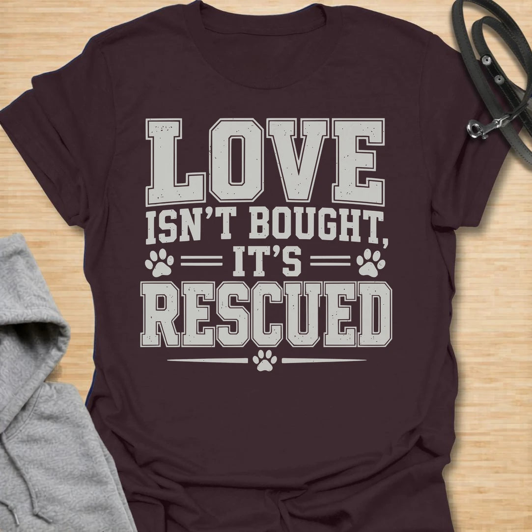 This Love Isn’t Bought, It’s Rescued t-shirt is made for rescue dog lovers who believe the best dogs are found through adoption and second chances. Featuring bold varsity-style lettering with paw print accents, this design has a simple, meaningful rescue-dog message that is easy to wear every day. Perfect for rescue dog moms, rescue dog dads, shelter dog adopters, foster families, animal lovers, and anyone who proudly supports dog rescue. Dark Chocolate