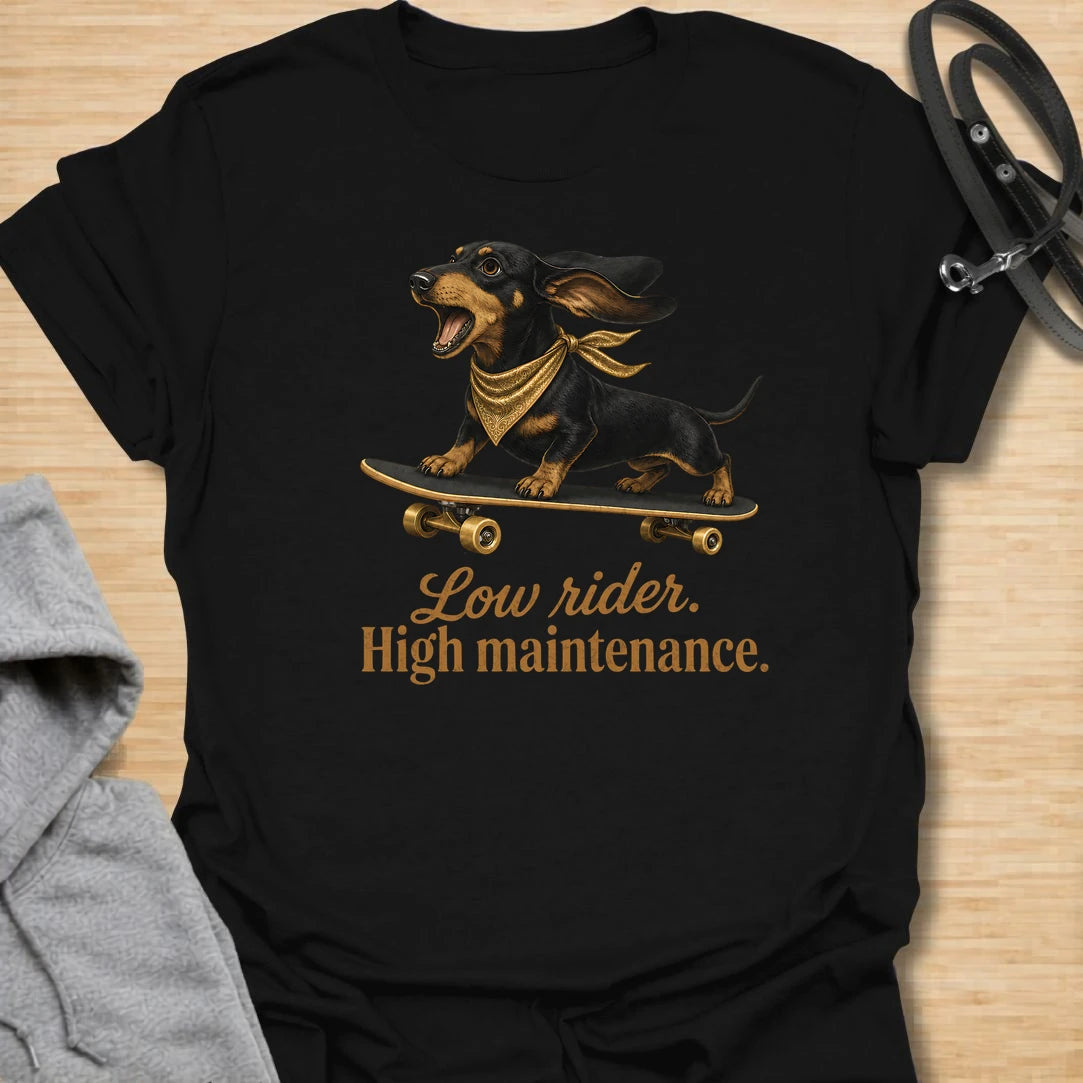 This Low Rider High Maintenance t-shirt is made for dachshund lovers who know their tiny-legged dog may ride low, but the demands are very high. Featuring a black and tan dachshund riding a skateboard with bold script lettering, this design has a funny, cool dog-parent feel. Perfect for dachshund moms, dachshund dads, wiener dog fans, rescue dog lovers, and anyone whose doxie is cute, costly, and completely worth it.