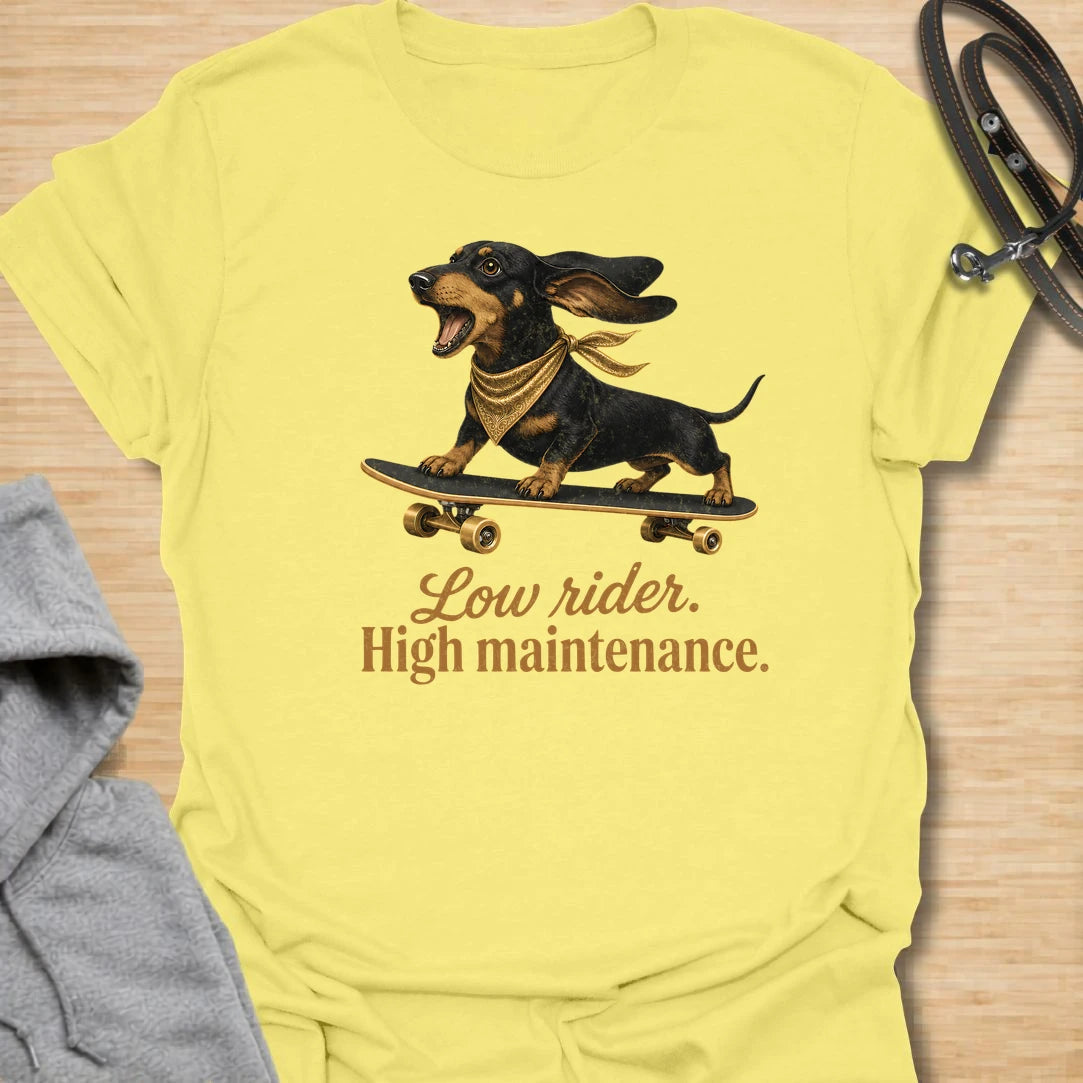 This Low Rider High Maintenance t-shirt is made for dachshund lovers who know their tiny-legged dog may ride low, but the demands are very high. Featuring a black and tan dachshund riding a skateboard with bold script lettering, this design has a funny, cool dog-parent feel. Perfect for dachshund moms, dachshund dads, wiener dog fans, rescue dog lovers, and anyone whose doxie is cute, costly, and completely worth it.
