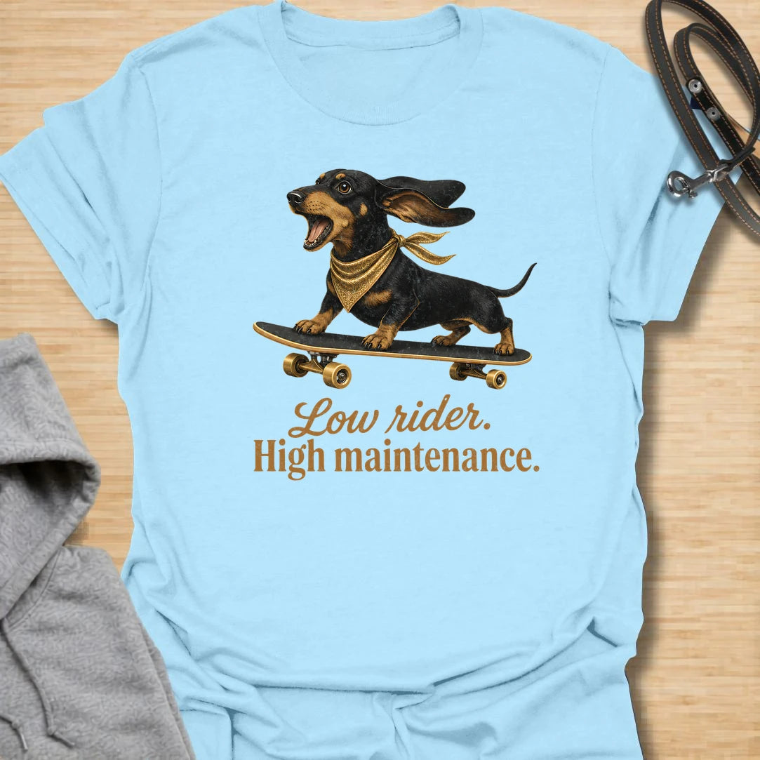 This Low Rider High Maintenance t-shirt is made for dachshund lovers who know their tiny-legged dog may ride low, but the demands are very high. Featuring a black and tan dachshund riding a skateboard with bold script lettering, this design has a funny, cool dog-parent feel. Perfect for dachshund moms, dachshund dads, wiener dog fans, rescue dog lovers, and anyone whose doxie is cute, costly, and completely worth it.