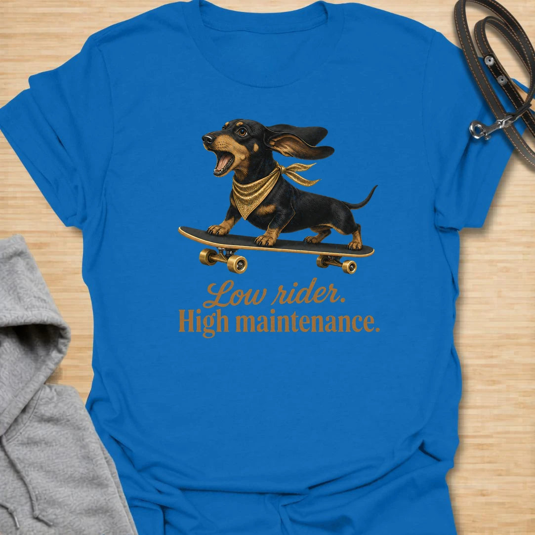This Low Rider High Maintenance t-shirt is made for dachshund lovers who know their tiny-legged dog may ride low, but the demands are very high. Featuring a black and tan dachshund riding a skateboard with bold script lettering, this design has a funny, cool dog-parent feel. Perfect for dachshund moms, dachshund dads, wiener dog fans, rescue dog lovers, and anyone whose doxie is cute, costly, and completely worth it.