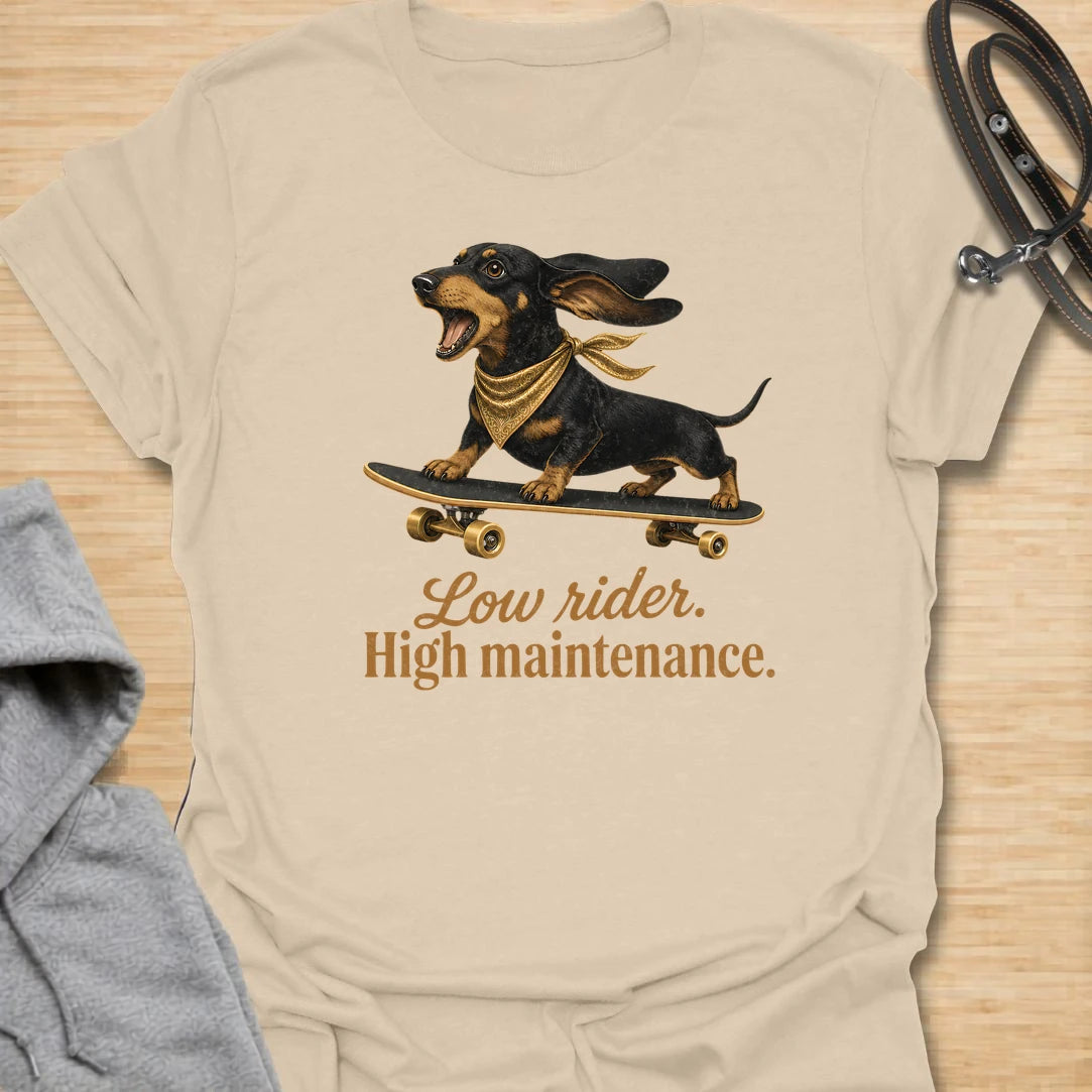 This Low Rider High Maintenance t-shirt is made for dachshund lovers who know their tiny-legged dog may ride low, but the demands are very high. Featuring a black and tan dachshund riding a skateboard with bold script lettering, this design has a funny, cool dog-parent feel. Perfect for dachshund moms, dachshund dads, wiener dog fans, rescue dog lovers, and anyone whose doxie is cute, costly, and completely worth it.