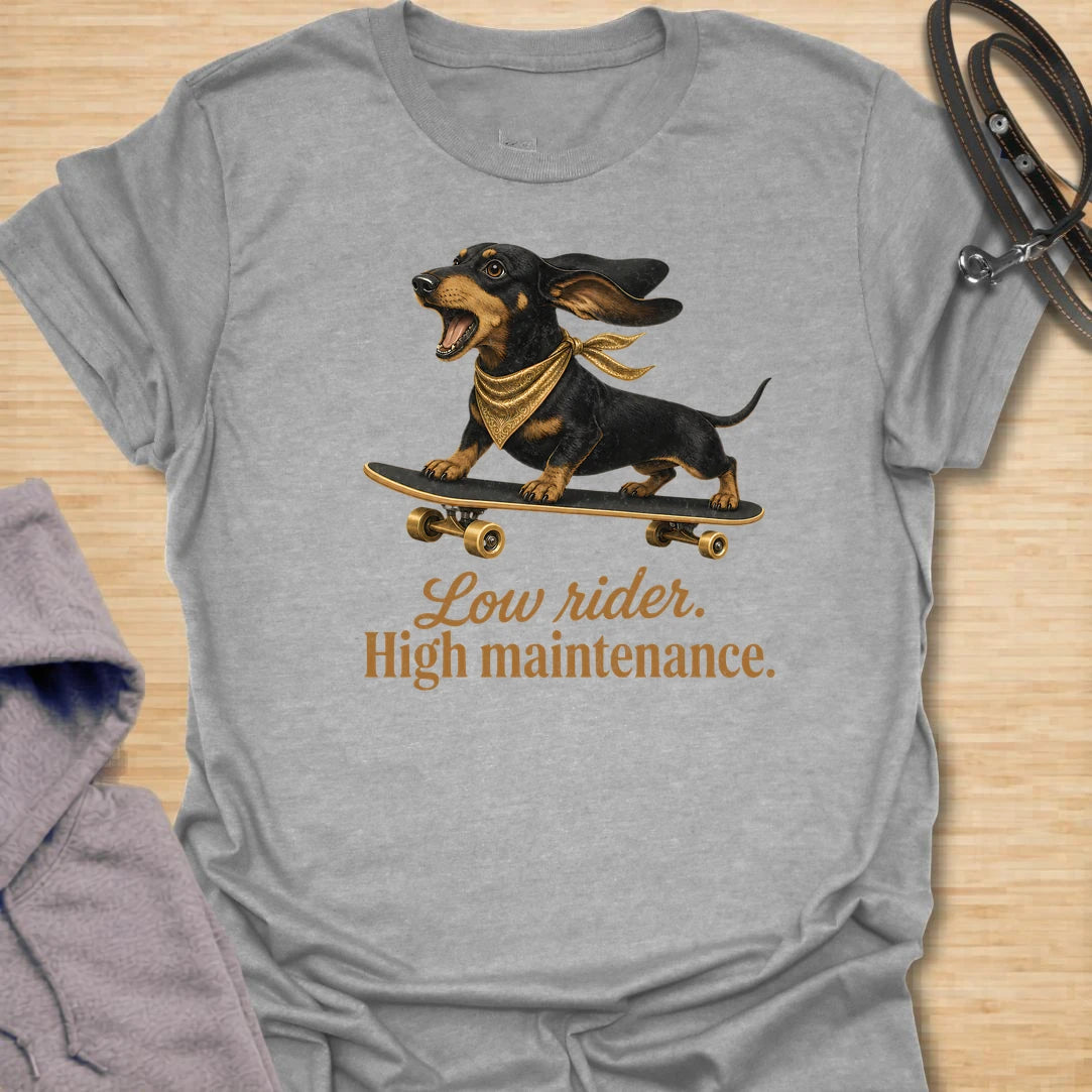 This Low Rider High Maintenance t-shirt is made for dachshund lovers who know their tiny-legged dog may ride low, but the demands are very high. Featuring a black and tan dachshund riding a skateboard with bold script lettering, this design has a funny, cool dog-parent feel. Perfect for dachshund moms, dachshund dads, wiener dog fans, rescue dog lovers, and anyone whose doxie is cute, costly, and completely worth it.