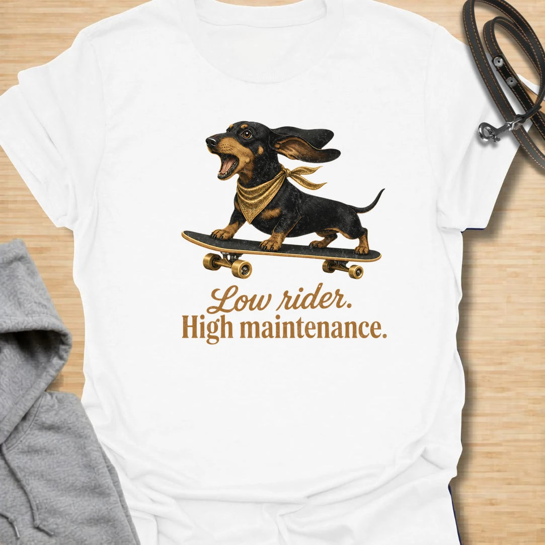 This Low Rider High Maintenance t-shirt is made for dachshund lovers who know their tiny-legged dog may ride low, but the demands are very high. Featuring a black and tan dachshund riding a skateboard with bold script lettering, this design has a funny, cool dog-parent feel. Perfect for dachshund moms, dachshund dads, wiener dog fans, rescue dog lovers, and anyone whose doxie is cute, costly, and completely worth it.